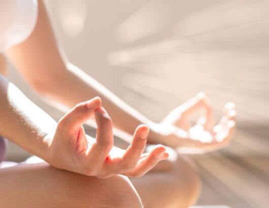 A person practicing meditation, sitting with their legs crossed and hands in a mudra position.