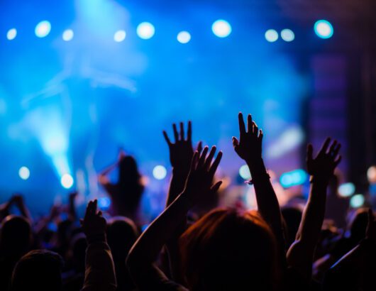 Crowd cheering on a band performing on stage.